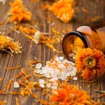 Homeopathic medicine, calendula dry flowers and wooden surface.